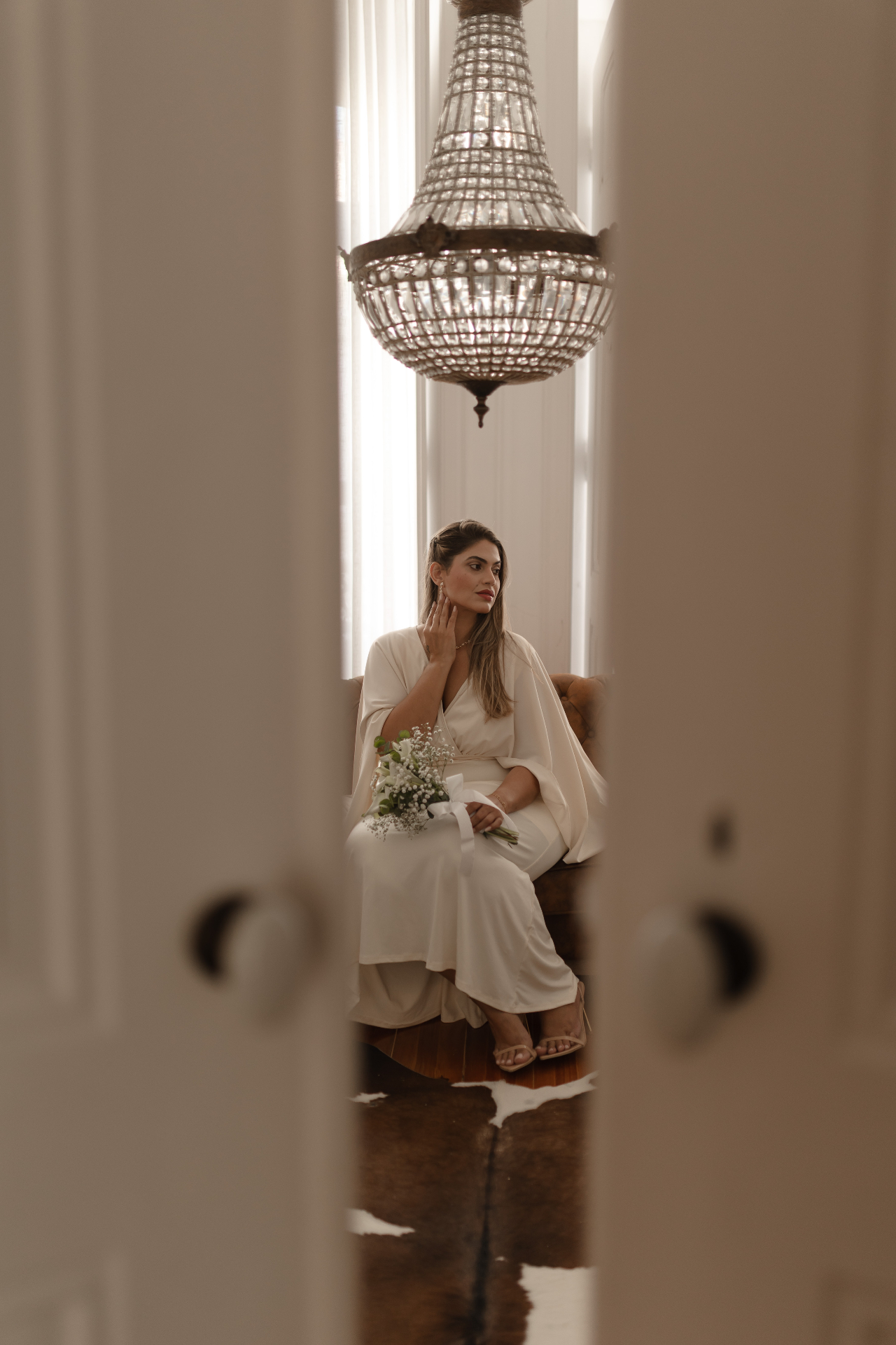 Noiva sentada sob um lustre de cristal num salão clássico
